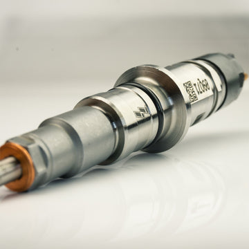Metallic diesel fuel injector shown at an angle, highlighting the nozzle tip and copper sealing washer clearly