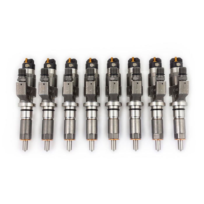 Complete set of eight LB7 Duramax fuel injectors with orange caps, lined up showing nozzle tips and top connectors